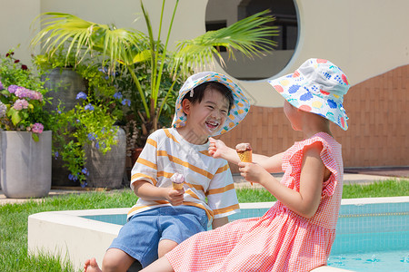 小男孩小女孩手拿冰淇淋坐在泳池边玩耍童年高清图片素材