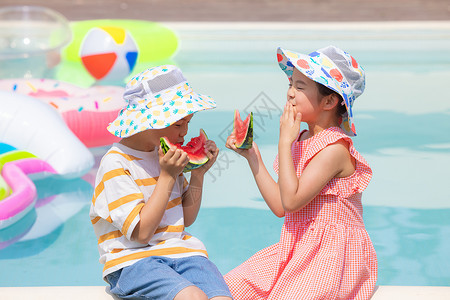 小男孩和小女孩面对面坐在泳池旁开心吃西瓜图片素材