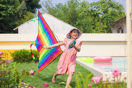 小女孩拿着风筝在草地上奔跑图片