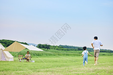 小孩在小男孩和爸爸在草坪上追逐打闹背影背景