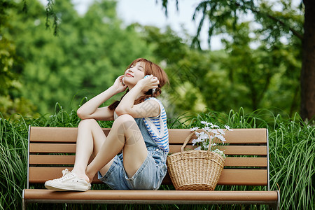 坐在花上的女孩坐在长椅上听音乐的夏日美女背景