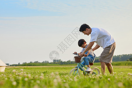 学自行车年轻爸爸陪伴小男孩学骑自行车背景