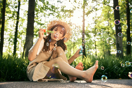 坐在草地前吹泡泡的清新夏日美女背景图片