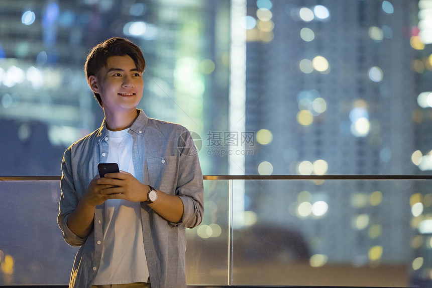 夜晚城市里玩手机的男青年图片