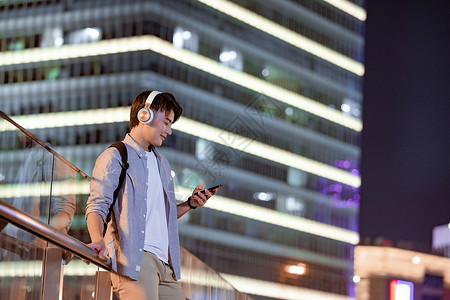下班路上听音乐看手机的年轻男性图片