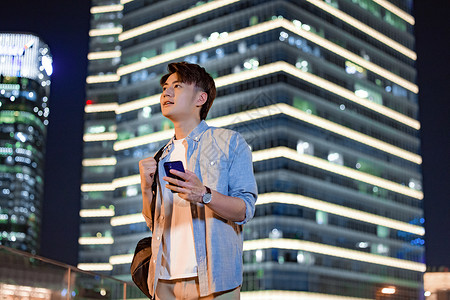 男青年夜晚行走在城市里高清图片