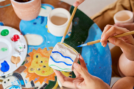 艺术老师教小朋友陶罐作画背景图片