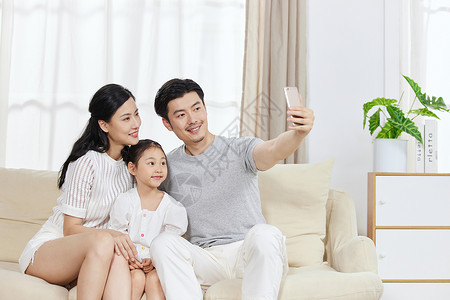 一家人在沙发上使用手机自拍图片