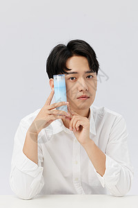 韩系男生手拿瓶装乳液护肤背景图片