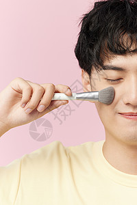 韩系男生手拿化妆刷闭眼特写背景图片