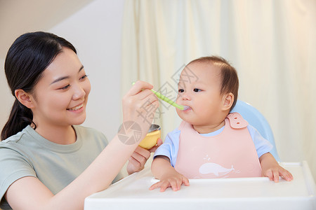 年轻宝妈喂食宝宝吃果泥背景图片