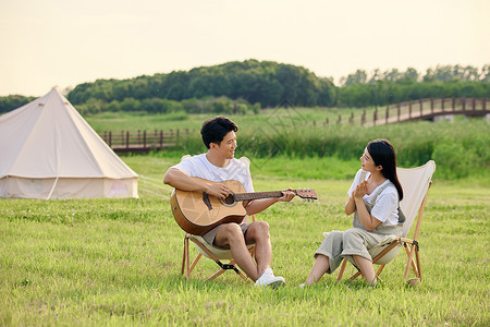 露营的情侣青年男女户外郊游露营弹吉他背景