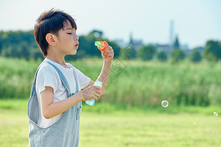 小男孩户外游玩吹泡泡草坪高清图片素材