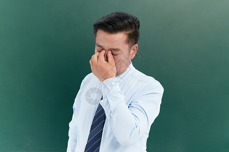 教师压力中年教授在黑板前做眼部按摩背景