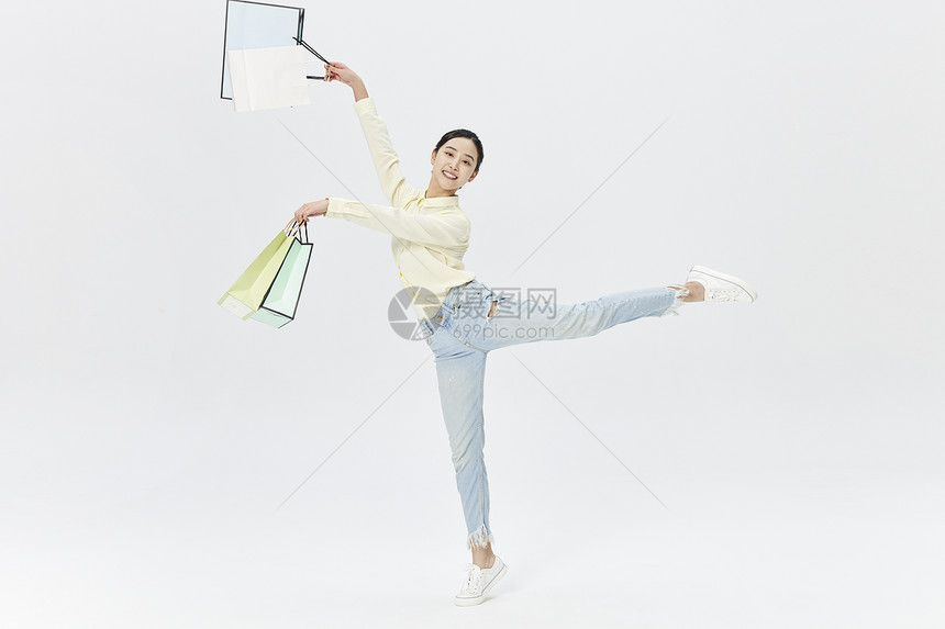 手拿购物袋跳舞的女性图片