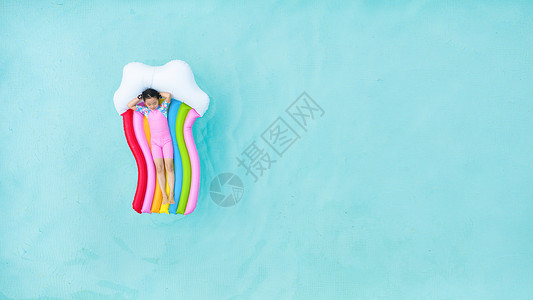 儿童小女孩躺在泳池彩虹气垫床上背景图片