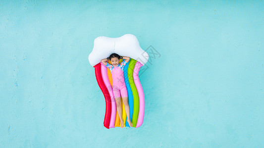 儿童小女孩躺在泳池彩虹气垫床上俯拍背景图片