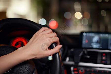 年轻女性司机夜间驾车手握方向盘特写图片