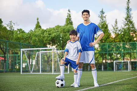 教练和男孩在足球场踢球形象背景图片