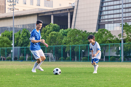 父子踢球父亲陪儿子在足球场踢足球背景