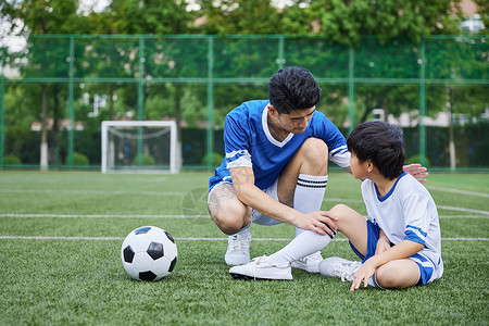 教练给男孩按摩受伤的膝盖高清图片