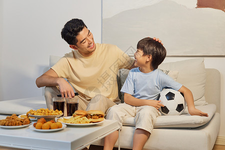 在家看足球赛爸爸和儿子坐沙发上看世界杯背景