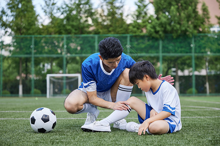 父亲给男孩检查受伤的膝盖图片