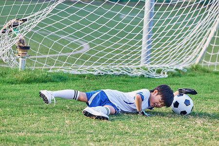 足球竞技小男孩踢足球摔倒背景