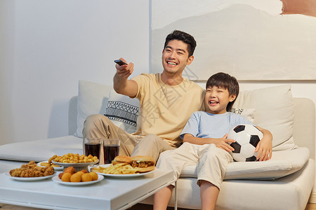 在家看足球赛爸爸和儿子坐沙发上开心看世界杯背景