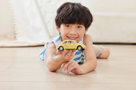 开汽车小男孩小男孩趴在地板上拿着玩具汽车背景