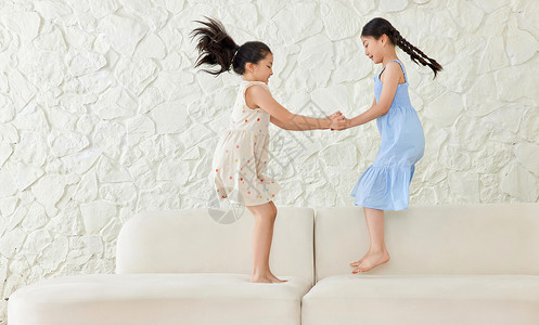 两个小女孩在沙发上蹦跳玩耍图片