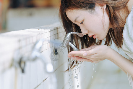 在洗手池捧起水的少女背景图片