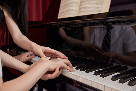 钢琴培训画册音乐教师教儿童弹奏钢琴特写背景