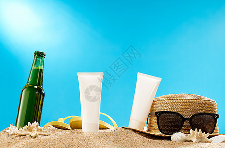 紫外线防护夏天沙滩上的啤酒和防晒霜背景