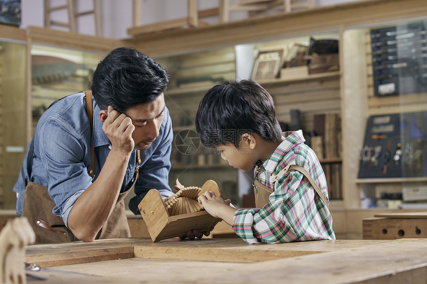 男木匠师傅和小男孩讲解手工音乐盒制作图片