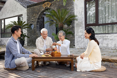 新婚夫妻陪伴老人过中秋节喝茶背景图片