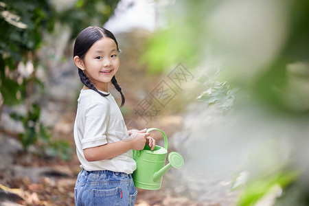 拿着洒水壶给植物浇水的小女孩图片