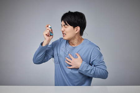 呼气年轻男性使用哮喘吸入器背景