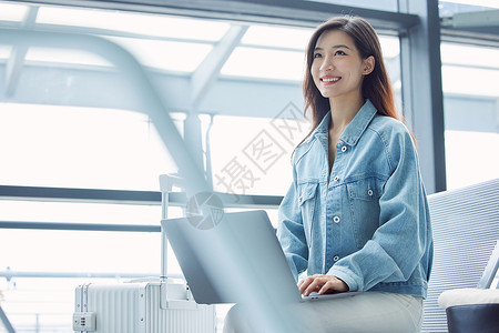 女性在机场使用笔记本电脑年轻高清图片素材