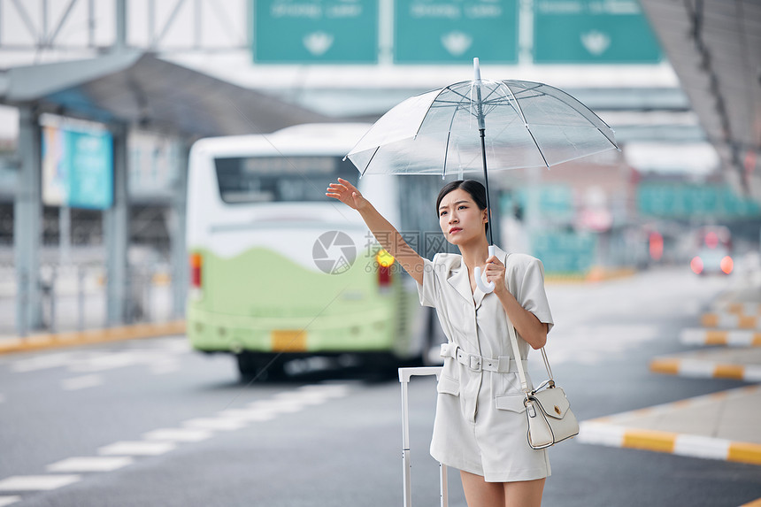 撑着伞在路边焦急打车的商务女性图片