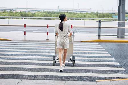 推着行李箱走在机场外的商务女性图片