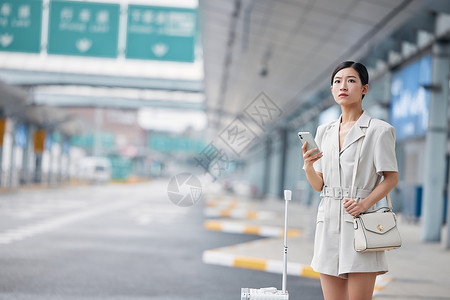 人行李箱机场室外打车的商务女性背景