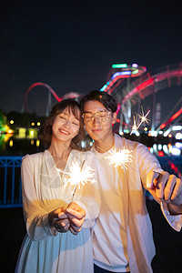 多彩清新烟花年轻情侣依偎在一起点燃烟花背景