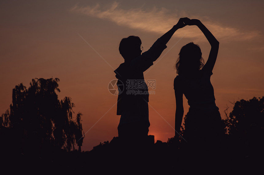 夕阳下牵手舞蹈的情侣剪影图片