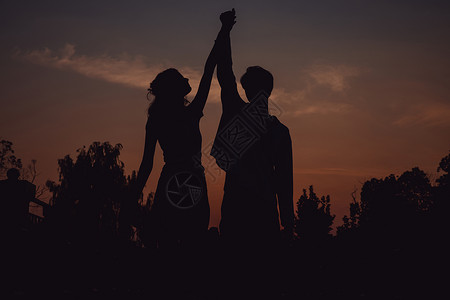 夕阳下牵着手舞蹈的情侣剪影图片