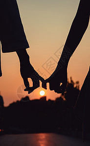 情侣手是素材夕阳下的情侣勾手剪影背景