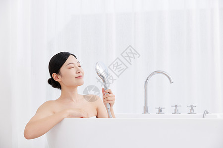 青年女性手拿花洒洗泡泡浴背景图片