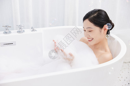 年轻女性躺在浴缸洗泡泡浴图片