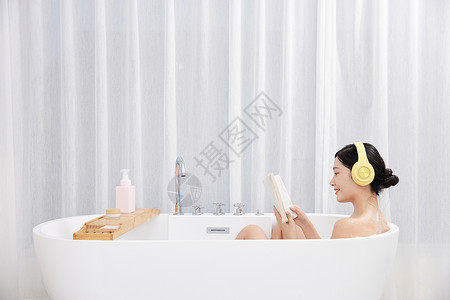 年轻女性居家泡澡听音乐看书图片