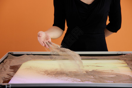 手绘糕点手绘沙画老师向沙画台上撒沙子背景